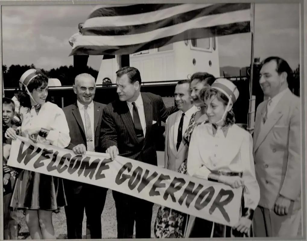 People with American Flag holding a "Welcome Governor" sign